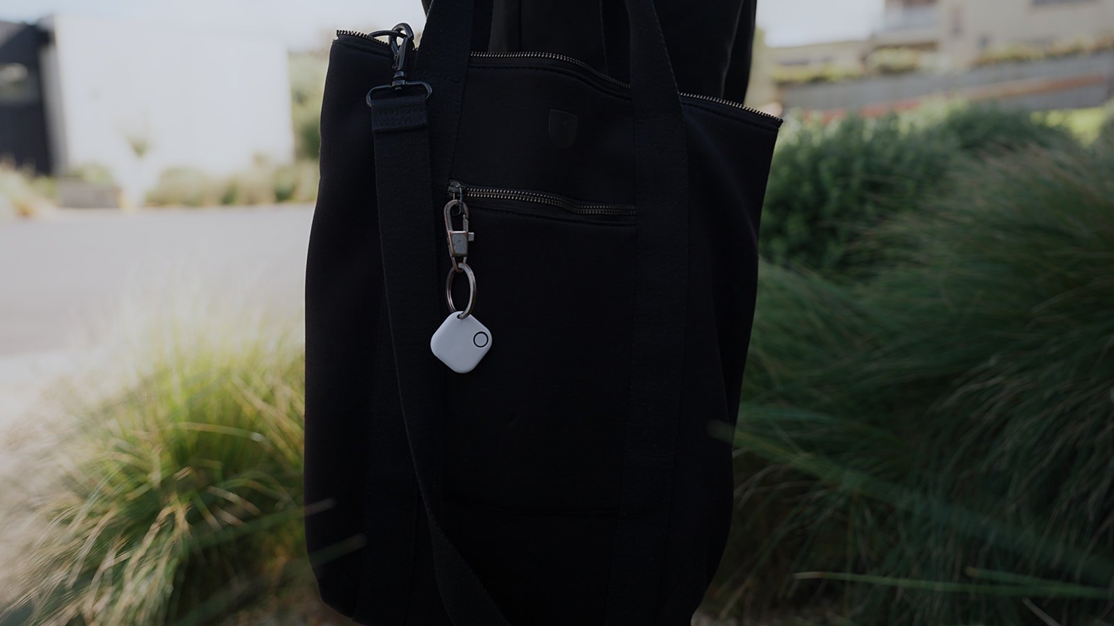 The jupyter Keyfob clipped to a tote bag in a coastal garden